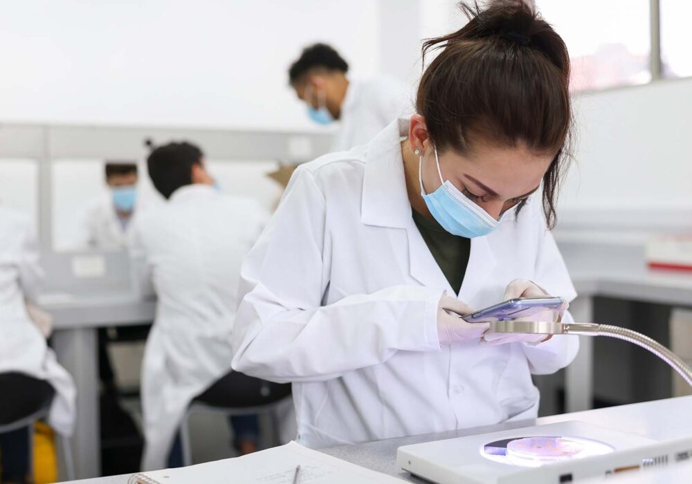 Female scientist taking a picture of her petri dish sample with her phone