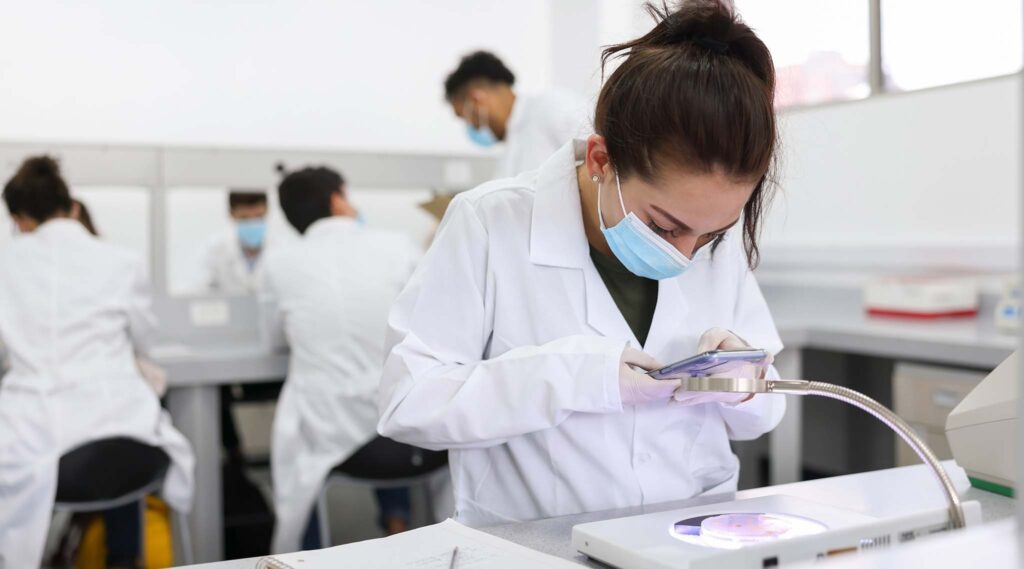 Female scientist taking a picture of her petri dish sample with her phone