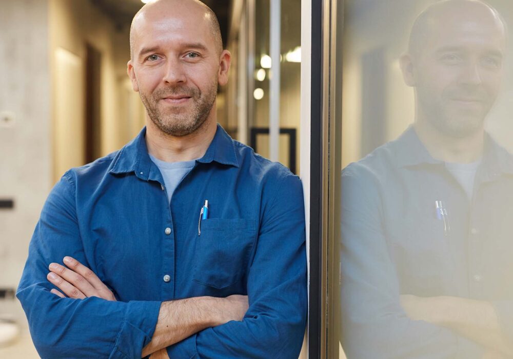 Man in blue shirt leaning on door/window frame