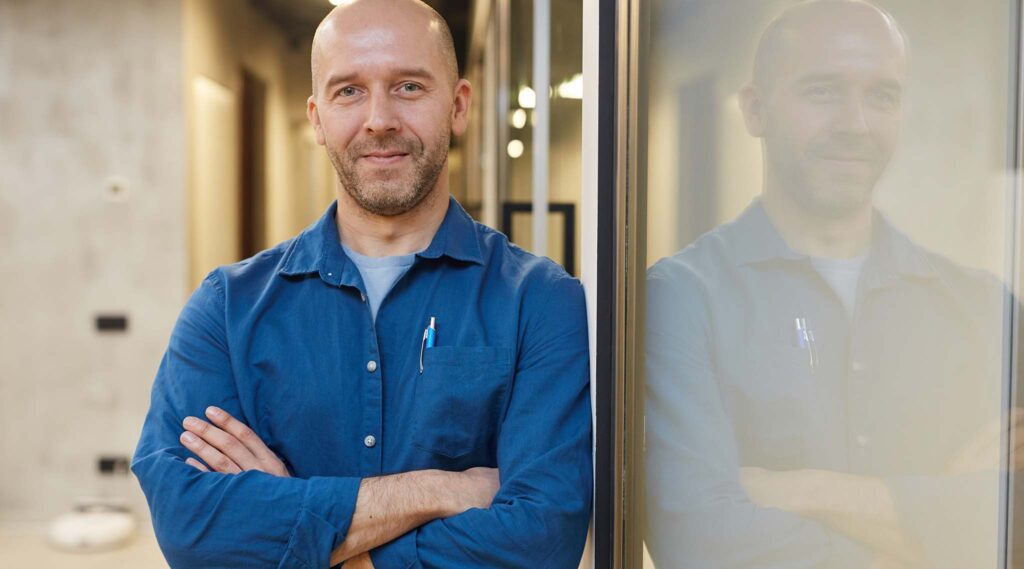 Man in blue shirt leaning on door/window frame