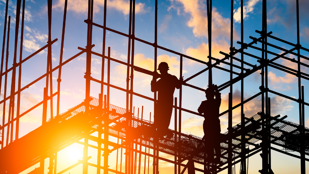 Construction workers on scaffolding obscured by the sun