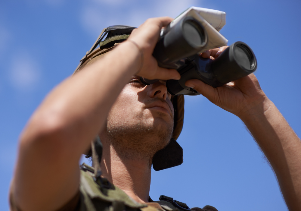 Military man with map looking through binoculars